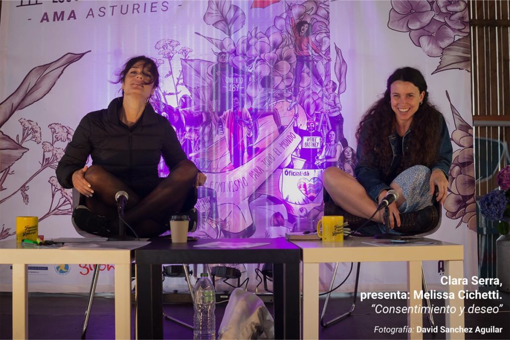 Clara Serra, durante su ponencia en la III Escuela Feminista AMA Asturies, con la gráfica de fondo de Eva Cortés Ilustra